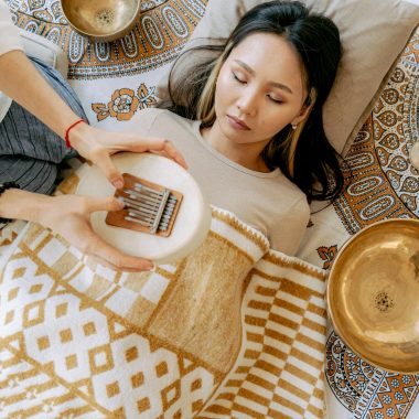A serene meditation scene with an Asian woman relaxing while listening to a kalimba, enhancing a peaceful atmosphere.
